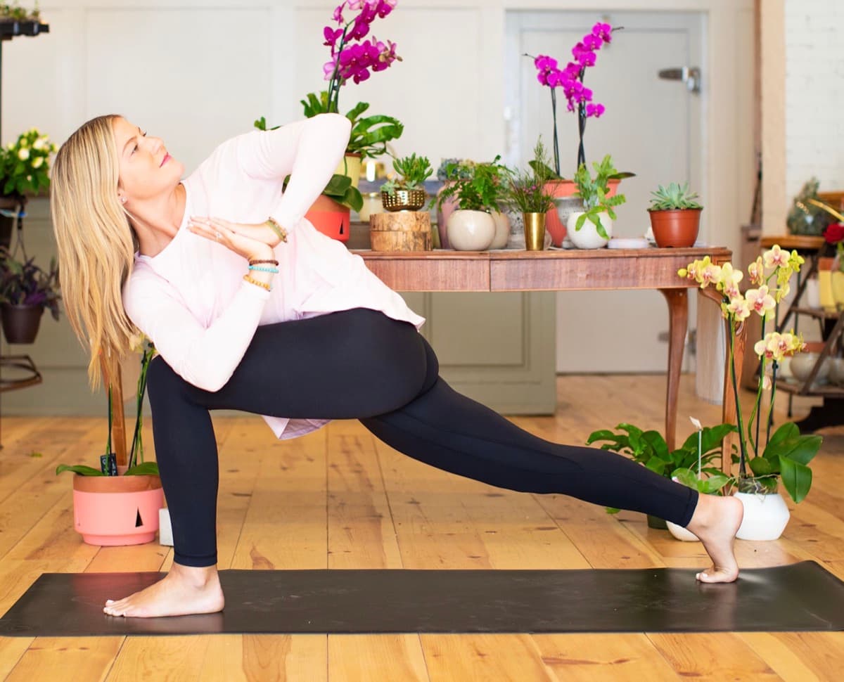Kyla MacKinnon teaching a revolved side angle yoga pose in a bright studio